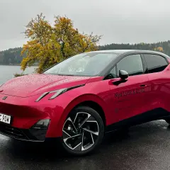 Röd elbil parkerad vid en sjö med höstfärger. En perfekt plats för en tco kalkyl.