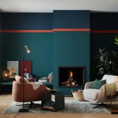 Moderne Wohnzimmer-farbgestaltung wand mit petrol, dunkelblau und korallenroten Akzenten. Gemütliche Sessel und Kamin sorgen für Wohlfühlatmosphäre.