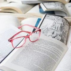 Różowe okulary leżą na otwartych książkach. Idealne do czytania po francusku, gdy tekst jest trudny.