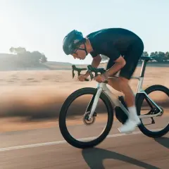 Kolarz w aerodynamicznej pozycji minimalizuje opory toczenia opon rowerowych, pędząc przez krajobraz.