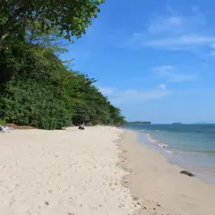 En avkopplande stranddag på Koh Jum. Lång, vit sandstrand kantad av frodig grönska och turkost hav.