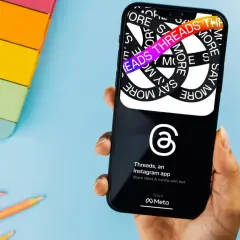 Dłoń trzyma smartfon z aplikacją Threads. Na ekranie widać hasła "Say More" i "Threads", co wyjaśnia, threads co to za aplikacja.
