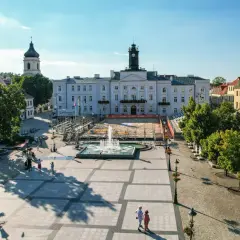 Stary Rynek Płock z ratuszem i fontanną w centrum. W tle widać kościoły i kolorowe kamienice.