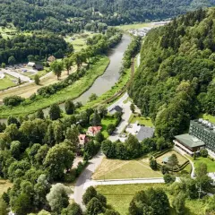 Malowniczy widok na Muszynę z rzeką i lasami. W oddali widać kompleks budynków, w tym sanatorium Revita.