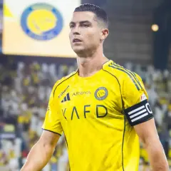 Cristiano Ronaldo w żółtej koszulce Al Nassr, z opaską kapitana na ramieniu, na tle trybun pełnych kibiców.