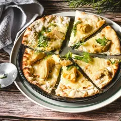 Eine köstliche Pizza Bianca mit Artischocken, Rucola und Pinienkernen, bereit zum Genießen.