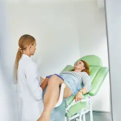 Fisioterapista pavimento pelvico visita una paziente sdraiata su un lettino ginecologico.