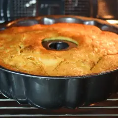 Bizcocho de manzana y naranja recién horneado en su molde, con un dorado perfecto. ¡Huele delicioso!