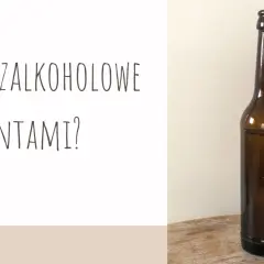 Brązowa butelka piwa na drewnianym blacie, obok grafika dwóch butelek i napis "Piwo bezalkoholowe z procentami?".