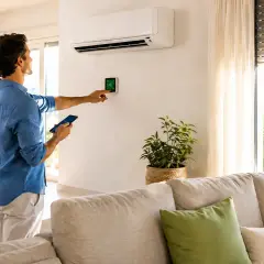 Uomo controlla termostato smart e smartphone, scoprendo nuovi modi per risparmiare energia in casa.