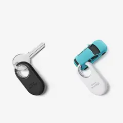 Biały i czarny smarttag przyczepione do miniaturowej walizki, kluczy, samochodu i roweru.