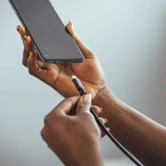 Dłoń z kablem USB przygotowuje się do podłączenia do telefonu, pokazując, jak naładować telefon telefonem.