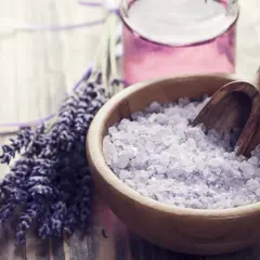 Lavendel badesalz selber machen: Eine Holzschale mit duftendem Lavendelsalz und ein Bündel frischer Lavendelblüten.