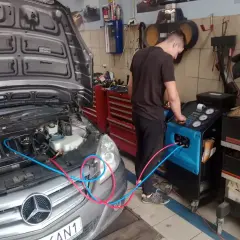 Mechanik wykonuje ozonowanie klimatyzacji w samochodzie Mercedes. Urządzenie do ozonowania podłączone jest do układu.