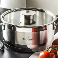 Stalowy garnek z logo Zwinger, idealny do przygotowania sosu pomidorowego. Obok nóż i świeże pomidory.