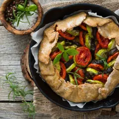 Une rustique quiche aux légumes, garnie de tomates, courgettes et aubergines, prête à être dégustée.
