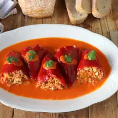 Pimientos del piquillo rellenos de atún y huevo, servidos en una salsa roja cremosa.