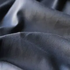 Plis du polyester tissu, d'une teinte gris foncé, créant des ombres douces et des reflets subtils.