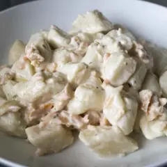 Puszyste gnocchi z ricottą i kawałkami łososia w kremowym sosie, podane w białej misce.