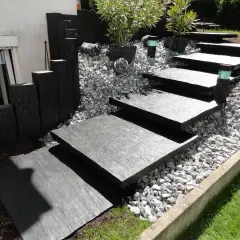 Moderner gartenweg am hang ohne stufen, mit dunklen Steinplatten und Kiesbett.