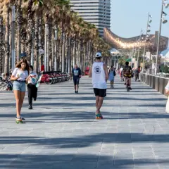 Spacer po promenadzie w Barcelonie, gdzie panuje przyjemna hiszpania temperatura roczna. Ludzie jeżdżą na deskorolkach i rowerach, ciesząc się słońcem.