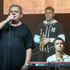 Kultowi artyści na scenie. Wokalista z mikrofonem, w tle trębacz i klawiszowiec. Ich kultowe utwory poruszają serca.