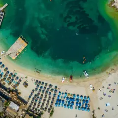 Widok z lotu ptaka na turkusowe morze i piaszczyste plaże Albanii, z rzędami leżaków i parasoli, idealne na wakacje.