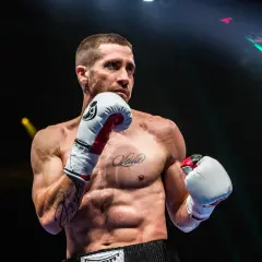 A boxer, possibly Jake Gyllenhaal, in an orthodox stance, ready to fight. His intense gaze suggests a southpaw opponent.