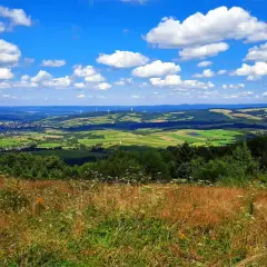 Widok z tokarnia szczyt na zielone wzgórza, pola i wiatraki pod błękitnym niebem z chmurami.
