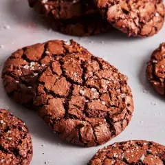 Knusprige brownie cookies mit Meersalzflocken, die auf einer hellen Oberfläche liegen.
