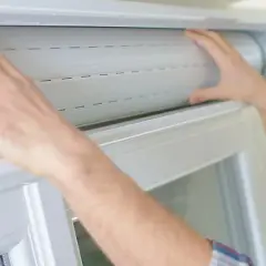 Mains manipulant un volet roulant blanc, étape clé pour savoir comment réparer un volet roulant.