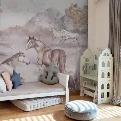 Urocza tapeta w koniki zdobi pokój dziecka. Na ścianie widać konie w biegu i odpoczywające, w otoczeniu gór i drzew.