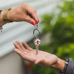 Una mano entrega una llave con un llavero de casa, simbolizando la permuta de viviendas entre particulares.