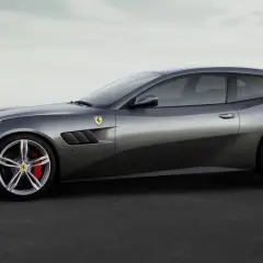 Szary Ferrari FF, sportowe kombi z charakterystycznymi wlotami powietrza i czerwonymi zaciskami hamulcowymi, prezentuje się na tle mglistego nieba.