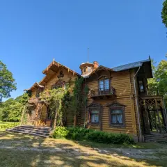 Drewniany dworek z werandą i balkonami, otoczony zielenią. Piękna leżajsk trasa widokowa.