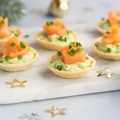 Aperitivos baratos para mucha gente: canapés de salmón y aguacate, decorados con cebollino y estrellas doradas.