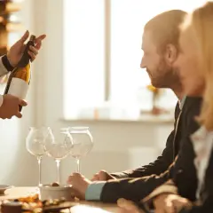Ein Sommelier präsentiert eine Weinflasche. Die Bedeutung eines Sommeliers liegt in seiner Expertise für Wein und Speisen.