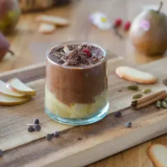 Délicieuse recette mousse poire chocolat, garnie de copeaux de chocolat et d'une framboise. Poires fraîches et épices sur fond de bois.