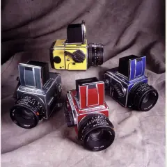 A collection of vintage Hasselblad 500c cameras in various colors: yellow, green, red, and blue.