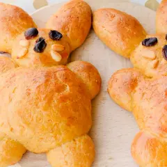Zwei goldbraune Osterhasen aus Hefeteig, dekoriert mit Rosinen und Mandeln. Perfekt zum Osterbacken mit Kindern.