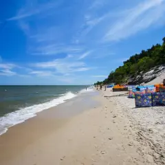 Słoneczna plaża w Chłapowie z kolorowymi parawanami, idealne miejsce na rodzinne wakacje i atrakcje dla dzieci.
