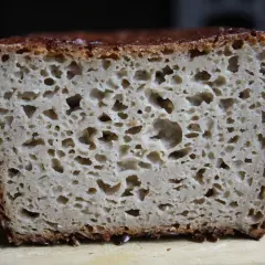 Przekrój chleba gryczanego z widoczną, porowatą strukturą i ciemną skórką.