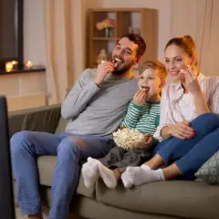 Rodzina ogląda fajne filmy dla dzieci, zajadając popcorn.
