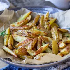 Klyftpotatis i airfryer, gyllene och krispiga, serverade med rosmarin. Perfekt tillbehör!