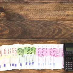 Banknoty euro i kalkulator na drewnianym tle.