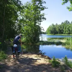 Rowerzysta odpoczywa nad jeziorem, ciesząc się pięknymi trasami rowerowymi w Olsztynie.