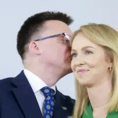 Szymon Hołownia szepcze coś do ucha swojej żonie Urszuli Brzezińskiej.