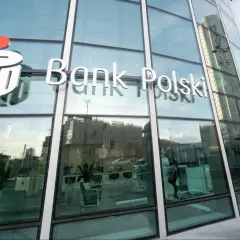 Logo PKO Bank Polski na szklanej fasadzie. W środku wnętrze banku, gdzie można założyć pko bp lokaty.