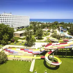 Kolorowy aquapark na plaży w Saharze, z hotelowcem w tle i błękitnym morzem.
