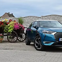 Niebieski DS 3 Crossback obok drewnianego wozu z kwiatami.